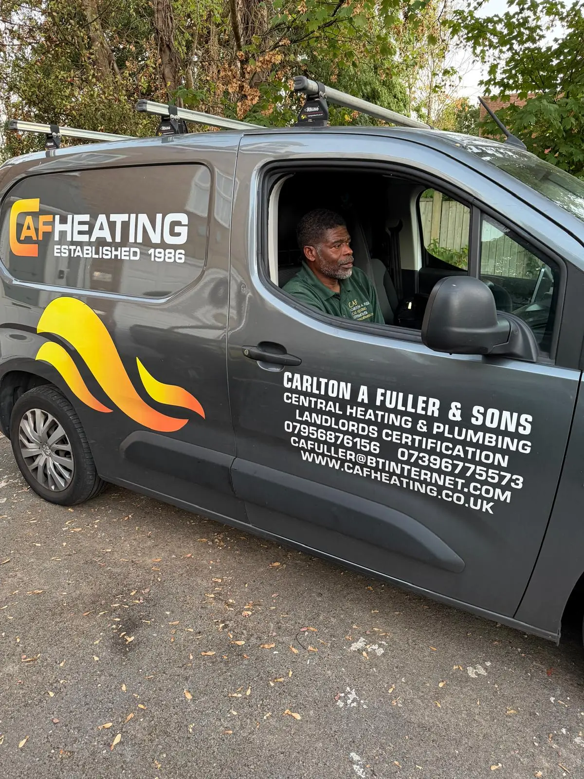 Carlton Fuller in the driver's seat of the CAF Heating van, wearing his green work polo